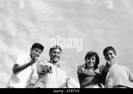 Famiglia assieme all'aperto, puntamento e sorridente in telecamera a basso angolo di visione Foto Stock