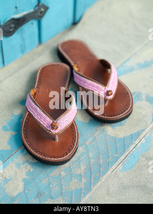 Coppia di perle rosa in pelle sandali estivi sulla sabbia di un pavimento in legno Foto Stock