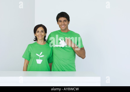 Uomo con annaffiatoio, in piedi accanto alla donna che indossa tee-shirt stampata con impianto grafico, ritratto Foto Stock