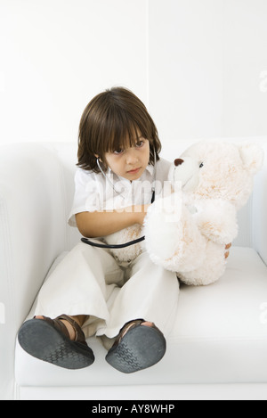 Little Boy riproduzione medico con il giocattolo imbottito, utilizzando uno stetoscopio Foto Stock