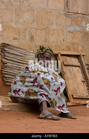 Un'anziana donna in Togo, Africa occidentale è avvolto in uno scialle e di seduta al di fuori della propria casa Foto Stock