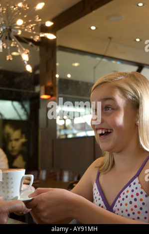 Ragazza nel Cafe di bere cioccolata calda con panna sul naso Foto Stock