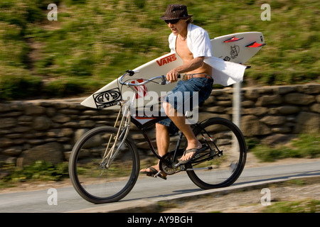 Surfer Alan Stokes in discesa in bicicletta con la tavola da surf, Cornwall, Regno Unito Foto Stock