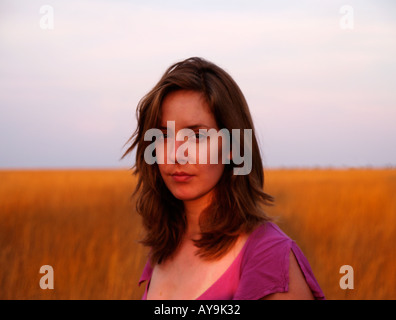 Giovane e bella ragazza la ventenne con espressione criptica fotografato in un campo al tramonto in Africa Foto Stock