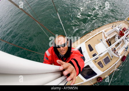 Uomo montante di arrampicata di yacht a vela, Cowes, Isle of Wight, Regno Unito Foto Stock