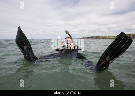 Scuba Diver regolazione della fotocamera mentre galleggiante sull'acqua Foto Stock