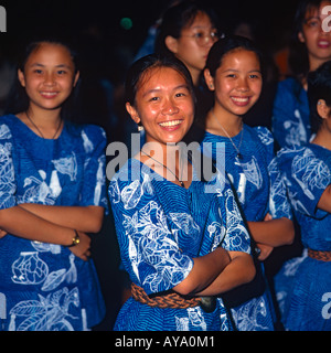 Tre donne cinesi ballerini Fijiano gruppo poste vestito in tropicale blu e bianco vestiti con altre ragazze in background Foto Stock