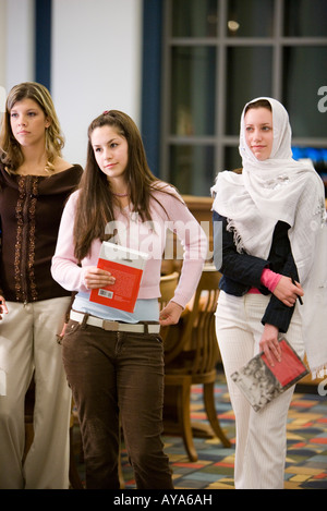 Tre giovani donne in piedi la biblioteca con libri Foto Stock