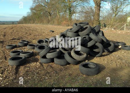 Ribaltamento illegale di pneumatici di veicoli scaricati in campo agricolo per evitare di pagare spese di smaltimento flytipping grande problema in campagna Essex Engalnd UK Foto Stock