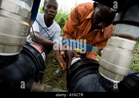 Gli uomini di pulizia sul filtro di irrigazione agricola della pompa del sistema Foto Stock