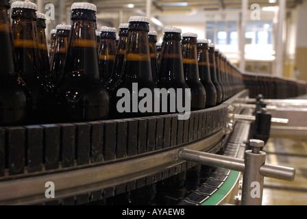 Linea di imbottigliamento presso una fabbrica di birra con linee di bottiglie di birra viene convogliato verso una macchina etichettatrice Foto Stock