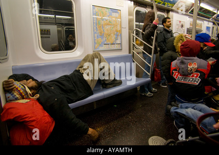 Un senzatetto uomo dorme su una sede metropolitana di New York City Foto Stock