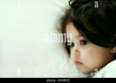 Bambina giacente a letto nel pensiero profondo Foto Stock