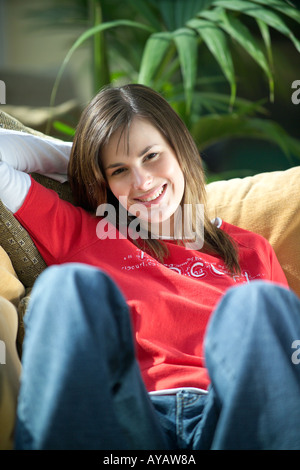 Ritratto di giovane donna rilassante sul divano di casa Foto Stock