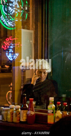 Una donna a parlare su un telefono cellulare in un ristorante di New York City Foto Stock