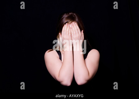 Ragazza nasconde il viso con le mani Foto Stock