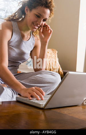 Close-up di giovane donna seduta su un divano con un computer portatile Foto Stock