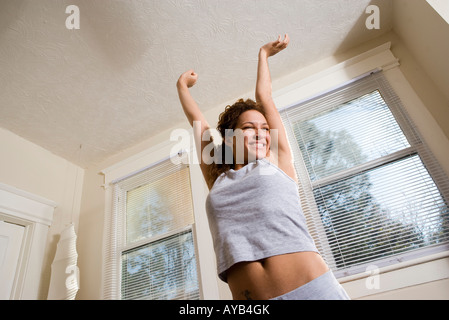 Basso angolo di visione di un felice e sorridente giovane donna stretching Foto Stock