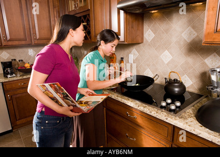 Asian madre e figlia la cottura nel wok azienda cookbook Foto Stock