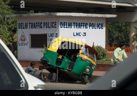 Ripartiti in giallo e verde tuk tuk taxi, al di fuori del traffico di Delhi la polizia booth, New Delhi, India. Foto Stock