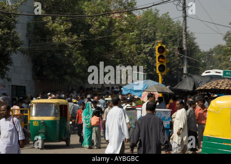 Pedoni e il verde e il giallo un tuk tuk taxi, New Delhi, India. Foto Stock