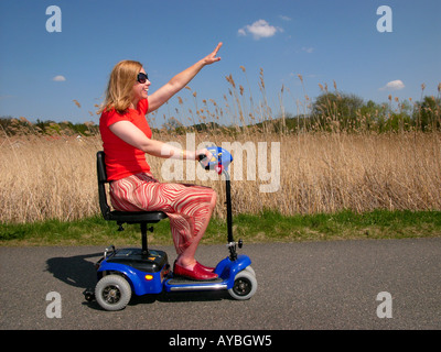 Donna sulla disabilità scooter divertimento in libertà di sole Foto Stock