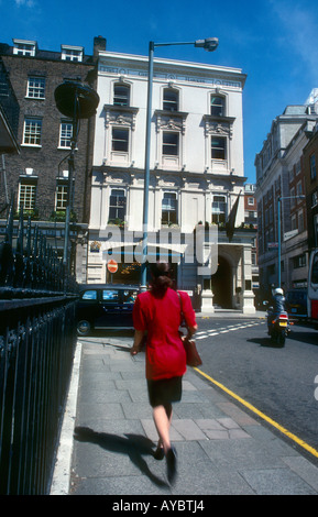 Donna elegante in giacca rossa shopping nelle esclusive storico Savile Row zona di Mayfair home di maestri sarti Foto Stock
