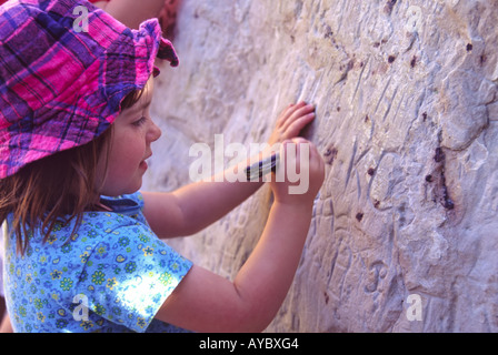 Un giovane visitatore lascia la sua propria graffiti su una dimostrazione di roccia in roccia di iscrizione, el Morro monumento nazionale, Nuovo Messico. Foto Stock