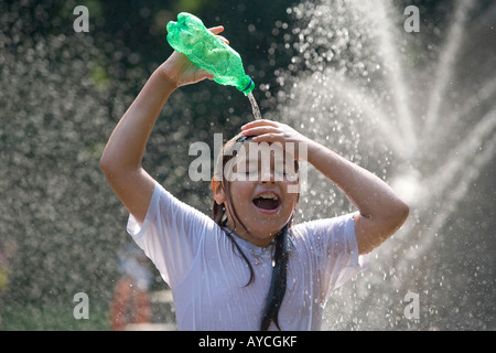 Una giovane ragazza ispanica non si raffredda in una fontana come anche lei si versa acqua sulla sua testa Foto Stock