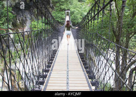 Donna attraversando il ponte di sospensione Foto Stock