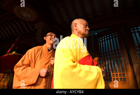 Il vecchio monaco gravi marciando con un giovane di ridere monaco buddista, durante una processione religiosa a Jingan Temple,a Shanghai in Cina Foto Stock