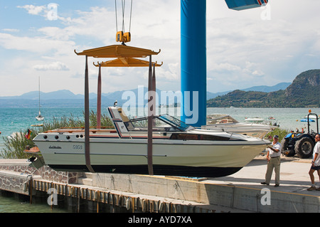 Il motoscafo sollevato al di fuori dell'acqua con una gru di banchina Garda Lago di Garda Italia Foto Stock