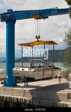 Il motoscafo sollevato al di fuori dell'acqua con una gru di banchina Garda Lago di Garda Italia Foto Stock