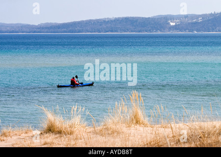 Un lone kayaker nelle calme acque turchesi di Sleeping Bear baia del Lago Michigan in primavera Foto Stock