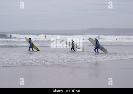 Tre Surfers andando per mare in Newquay Devon Foto Stock