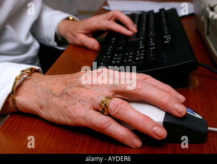 Donna anziana le mani sul mouse e tastiera Foto Stock