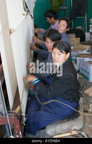 Esperto lavoratori tibetano tessitura di un tappeto in seta in una piccola fabbrica a Lhasa il Tibet, le loro mani una sfocatura come tessono la moquette Foto Stock