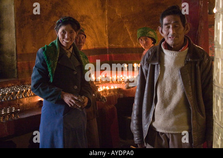 Pellegrini tibetani che pongono di fronte a un santuario di burro di yak candele in un piccolo monastero a Lhasa il Tibet Foto Stock