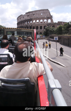 Torna a vedere i turisti a bordo dell'autobus rosso Stop & Go a due piani scoperto presso lo storico anfiteatro del Colosseo nella calda giornata di sole a Roma in Italia Foto Stock