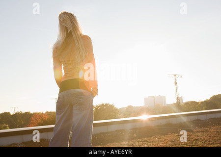 Giovane donna che guarda verso il sole Foto Stock