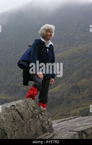 Il camminatore femmina in piedi su una roccia in Scozia Foto Stock