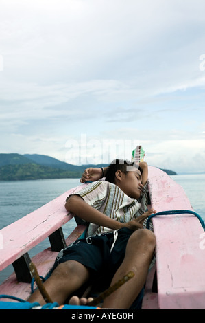 Fisherman's figlio dorme sulla prua di un'Indonesian Proa Foto Stock