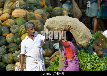 Donna che trasportano sacchi di tela di produrre in un mercato ortofrutticolo di Madurai India del Sud Foto Stock