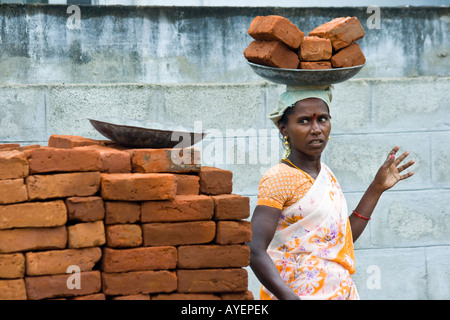 Donna che la porta in mattoni a un cantiere in Tiruchirappalli o Trichy India del Sud Foto Stock