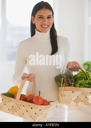 Donna che trasportano cesti di frutta e verdura Foto Stock