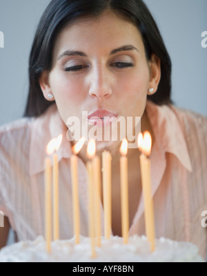 Donna che spegne le candeline sulla torta del compleanno Foto Stock