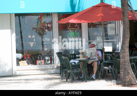 Uomo che legge un giornale in una caffetteria all'aperto a Fort Lauderdale, Florida, Stati Uniti. Foto Stock