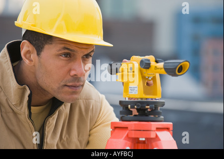 Maschio africano surveyor guardando attraverso il dispositivo di misurazione Foto Stock