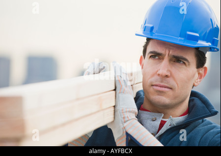 Costruzione maschio lavoratore azienda pila di legname Foto Stock