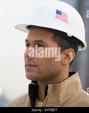 Maschio africano lavoratore edile con bandiera americana su elmetto Foto Stock